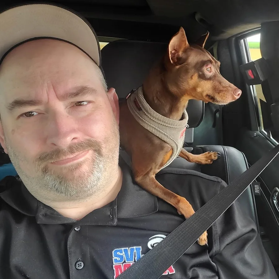Nathan Moore in the chase vehicle with his dog Niko riding on his shoulder